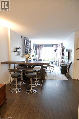 Open-concept living area featuring wood-finish flooring, a breakfast bar with built-in seating, recessed lighting, and wall-mounted shelving - 175 Hunter Street E Unit# 301, Hamilton, ON - Indoor