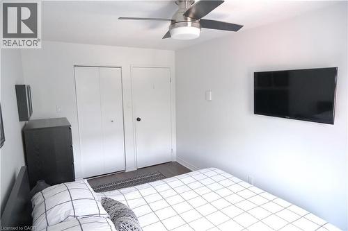 Bright interior space featuring wood-finish flooring, a contemporary ceiling fan, and two white doors - 175 Hunter Street E Unit# 301, Hamilton, ON - Indoor Photo Showing Bedroom