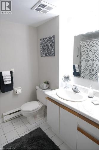 Bathroom featuring white tile flooring, a white toilet, and a vanity with white cabinetry, a light-colored countertop, and an integrated sink - 175 Hunter Street E Unit# 301, Hamilton, ON - Indoor Photo Showing Bathroom