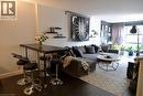 Open-concept living area featuring dark wood-finish flooring, a full-height window, and light-colored walls - 175 Hunter Street E Unit# 301, Hamilton, ON  - Indoor Photo Showing Other Room 