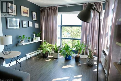 Room featuring dark wood-finish flooring, a full-height window with a metal grid, and a dark accent wall - 175 Hunter Street E Unit# 301, Hamilton, ON - Indoor