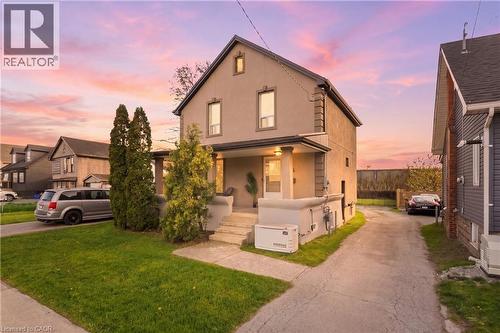 Two-story residence featuring a covered front porch, stucco exterior finish, and a paved side driveway - 204 Beach Boulevard, Hamilton, ON - Outdoor