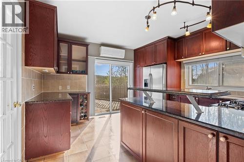Kitchen featuring dark wood cabinetry, a central island with an integrated breakfast bar, and dark stone countertops - 204 Beach Boulevard, Hamilton, ON - Indoor Photo Showing Kitchen