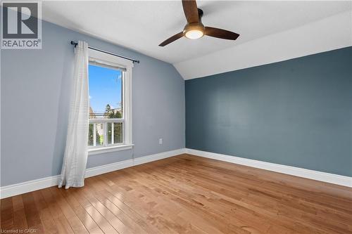 Hardwood flooring, painted walls with an accent wall, a window with exterior visibility, a ceiling fan with integrated lighting, and white baseboards - 204 Beach Boulevard, Hamilton, ON - Indoor Photo Showing Other Room