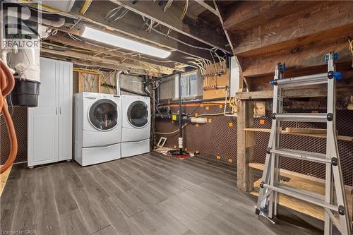 Utility area featuring wood-finish flooring, white built-in cabinetry, exposed wood ceiling beams, and a window - 204 Beach Boulevard, Hamilton, ON - Indoor Photo Showing Laundry Room
