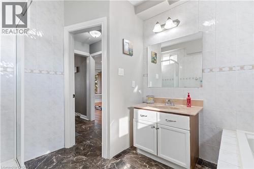 Bathroom featuring a white vanity with a light-toned countertop, a large mirror, and wall-mounted lighting - 204 Beach Boulevard, Hamilton, ON - Indoor Photo Showing Bathroom