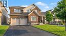 Brick and siding exterior featuring a two-car garage with panel doors, a paved driveway, and a covered front entry with railing - 123 Rea Drive, Fergus, ON  - Outdoor With Facade 