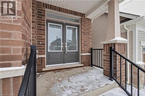 Brick facade with a covered porch featuring dual entry doors with glass panels, a transom window, and a concrete landing - 123 Rea Drive, Fergus, ON - Outdoor With Exterior