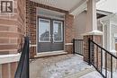 Brick facade with a covered porch featuring dual entry doors with glass panels, a transom window, and a concrete landing - 123 Rea Drive, Fergus, ON  - Outdoor With Exterior 