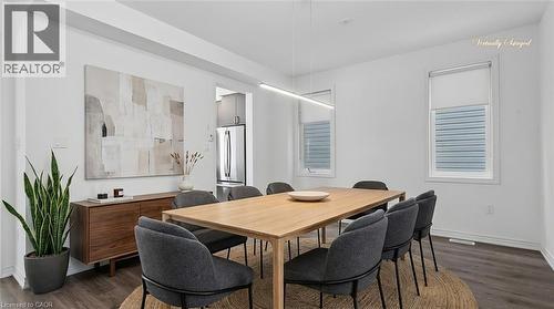 Open-concept dining area featuring wood-finish flooring, white walls, and two windows with roller shades - 123 Rea Drive, Fergus, ON - Indoor Photo Showing Dining Room