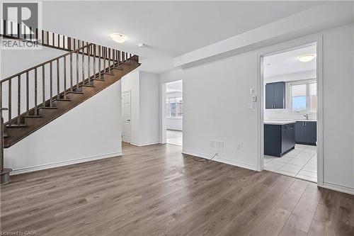 Open-concept living area featuring wood-finish flooring and a staircase with dark wood railings - 123 Rea Drive, Fergus, ON - Indoor Photo Showing Other Room