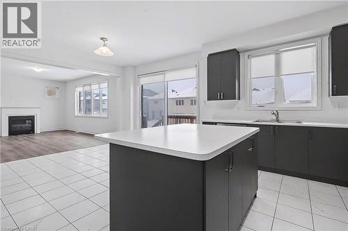 Kitchen featuring a central island with a solid surface countertop, dark cabinetry, and white tile flooring - 123 Rea Drive, Fergus, ON - Indoor Photo Showing Kitchen With Double Sink