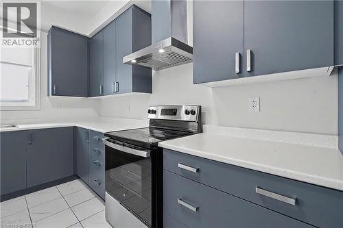 Contemporary kitchen featuring blue-gray cabinetry, white countertops, and a stainless steel range with overhead ventilation - 123 Rea Drive, Fergus, ON - Indoor Photo Showing Kitchen