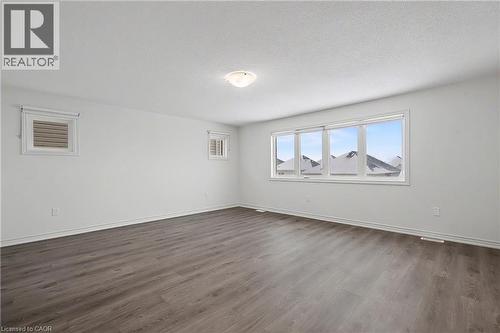 Spacious room featuring wood-finish flooring, white baseboards, and bright white walls - 123 Rea Drive, Fergus, ON - Indoor Photo Showing Other Room
