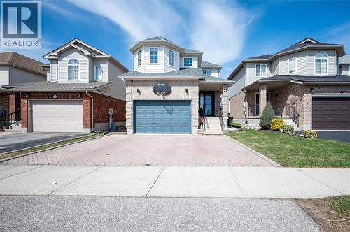 Two-story residence featuring light brick and siding exterior, a prominent octagonal bay window, and a blue garage door - 30 Heatherwood Place, Kitchener, ON - Outdoor With Facade