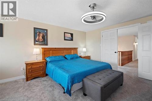 Carpeted bedroom featuring a wooden headboard, light beige wall paint, and a contemporary ceiling fan with integrated lighting - 30 Heatherwood Place, Kitchener, ON - Indoor Photo Showing Bedroom