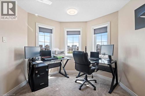 Room with light beige walls and carpeting features multiple windows with white trim and dark roller blinds, a ceiling-mounted light fixture, and white baseboards - 30 Heatherwood Place, Kitchener, ON - Indoor Photo Showing Office
