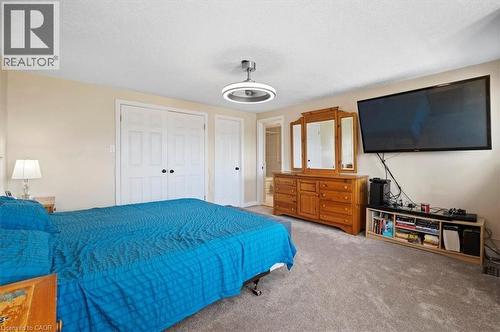 Plush carpeted bedroom featuring neutral wall tones, white bi-fold closet doors, and a modern ceiling fan with integrated lighting - 30 Heatherwood Place, Kitchener, ON - Indoor Photo Showing Bedroom