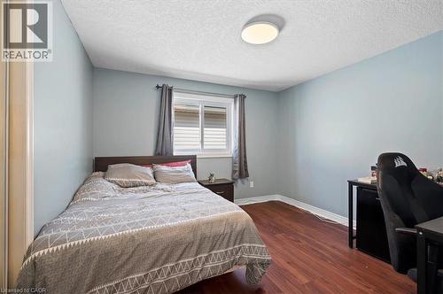 Bedroom featuring wood-finish flooring, light blue painted walls, a window with horizontal blinds, a ceiling-mounted light fixture, and white baseboards - 30 Heatherwood Place, Kitchener, ON - Indoor Photo Showing Bedroom