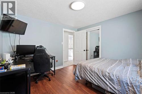Room featuring wood-finish flooring, light blue walls, and a white ceiling with a flush-mount light fixture - 30 Heatherwood Place, Kitchener, ON - Indoor Photo Showing Bedroom