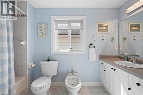 Full bathroom featuring a single window, tiled shower surround with decorative accent, toilet, bidet, and a vanity with white cabinetry, a single basin sink, and a countertop - 30 Heatherwood Place, Kitchener, ON - Indoor Photo Showing Bathroom