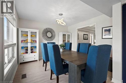 Dining space featuring light wood-finish flooring, ample natural light from multiple windows, a modern pendant light fixture, and an open doorway to an additional room - 30 Heatherwood Place, Kitchener, ON - Indoor Photo Showing Dining Room