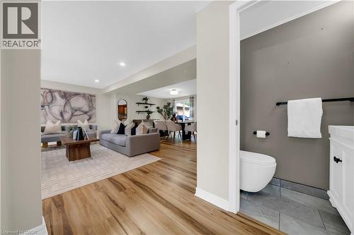 Powder room featuring a wall-mounted toilet, white vanity with black hardware, and gray tile flooring - 26 Peachtree Crescent, Cambridge, ON - Indoor
