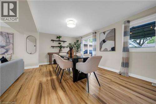 Dining area featuring wood-finish flooring, a contemporary ceiling light fixture, a sliding glass door, and a large window with white trim - 26 Peachtree Crescent, Cambridge, ON - Indoor Photo Showing Dining Room