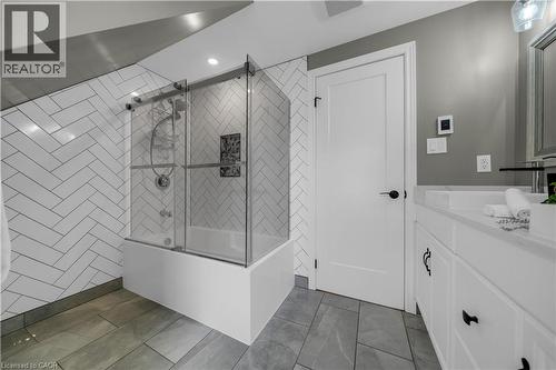 Contemporary bathroom featuring a bathtub with a sliding glass enclosure, herringbone pattern wall tile, and recessed lighting - 26 Peachtree Crescent, Cambridge, ON - Indoor Photo Showing Bathroom