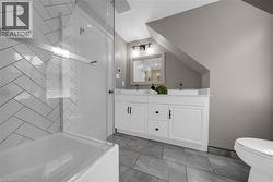 Bathroom featuring a dual vanity with white cabinetry and black hardware - 