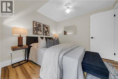 Wood-finish flooring throughout, featuring a white solid-core door with matte black hardware, and a ceiling-mounted light fixture - 26 Peachtree Crescent, Cambridge, ON - Indoor Photo Showing Bedroom