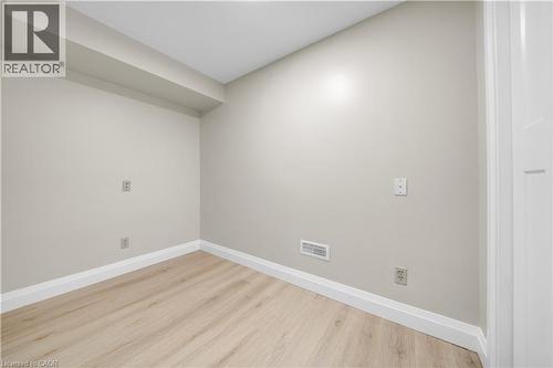 Neutral-toned room featuring light wood-finish flooring, white baseboards, and a contemporary white interior door with panel detailing - 26 Peachtree Crescent, Cambridge, ON - Indoor Photo Showing Other Room