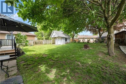 Expansive grassy lawn bordered by mature trees and a wooden fence - 26 Peachtree Crescent, Cambridge, ON - Outdoor With Deck Patio Veranda