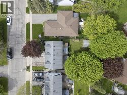 Single-story property with a brown shingle roof, featuring a private backyard with established green lawn and mature trees - 