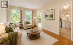 Living area with wood-finish flooring, two large windows, and a neutral colour palette.  Photo  Virtually Staged - 