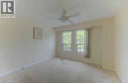 Bright room featuring dual windows, a ceiling fan, and light-colored carpeting - 
