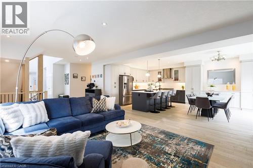 Open-concept living area featuring light wood-finish flooring, recessed lighting, a modern kitchen with a central island, stainless steel appliances, and an integrated dining area - 581 Doonwoods Crescent, Kitchener, ON - Indoor Photo Showing Living Room