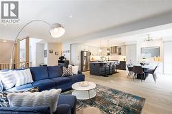 Open-concept living area featuring light wood-finish flooring, recessed lighting, a modern kitchen with a central island, stainless steel appliances, and an integrated dining area - 