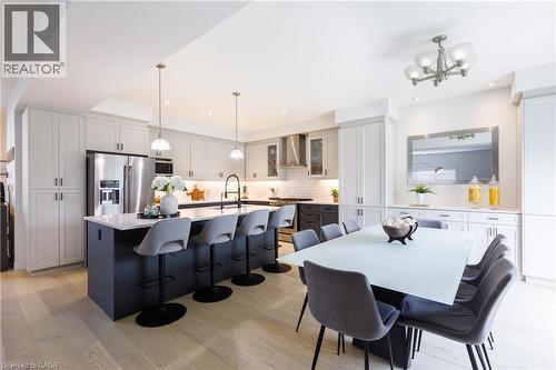 Open-concept kitchen featuring an oversized island with seating, pendant lighting, stainless steel appliances, and light wood-finish flooring - 581 Doonwoods Crescent, Kitchener, ON - Indoor