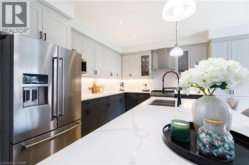 Contemporary kitchen featuring a large white countertop island, stainless steel appliances, two-tone cabinetry, subway tile backsplash, and recessed lighting - 581 Doonwoods Crescent, Kitchener, ON - Indoor Photo Showing Kitchen With Stainless Steel Kitchen With Double Sink With Upgraded Kitchen