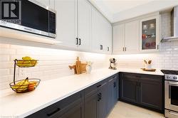 Contemporary kitchen featuring two-tone cabinetry with matte black hardware, white subway tile backsplash, and under-cabinet lighting - 