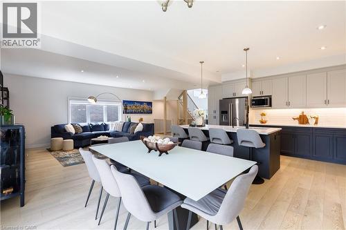 Open-concept living space featuring light wood-finish flooring, recessed lighting, a modern kitchen island with pendant lighting, stainless steel appliances, and built-in cabinetry - 581 Doonwoods Crescent, Kitchener, ON - Indoor