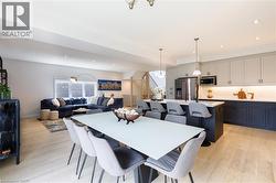 Open-concept living space featuring light wood-finish flooring, recessed lighting, a modern kitchen island with pendant lighting, stainless steel appliances, and built-in cabinetry - 