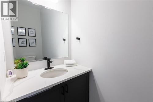 Bathroom vanity featuring a rectangular sink set into a white countertop, matte black faucet, and dark cabinetry - 581 Doonwoods Crescent, Kitchener, ON - Indoor Photo Showing Bathroom