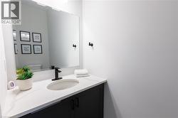 Bathroom vanity featuring a rectangular sink set into a white countertop, matte black faucet, and dark cabinetry - 