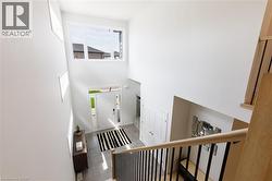 Bright foyer with a double-height ceiling, large transom windows, light-toned tile flooring, and a contemporary white front door with sidelights - 