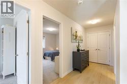 Interior hallway featuring wood-finish flooring, white trim, and light wall paint - 