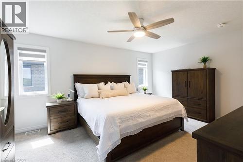 Carpeted room featuring a ceiling fan with integrated lighting, two windows with blinds, and white walls - 581 Doonwoods Crescent, Kitchener, ON - Indoor Photo Showing Bedroom