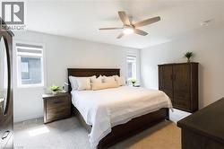 Carpeted room featuring a ceiling fan with integrated lighting, two windows with blinds, and white walls - 
