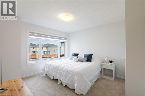 Bright bedroom featuring a large window, neutral wall paint, and soft carpet flooring - 581 Doonwoods Crescent, Kitchener, ON - Indoor Photo Showing Bedroom